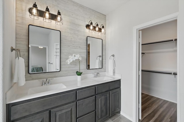 bathroom featuring double vanity, a sink, and a spacious closet