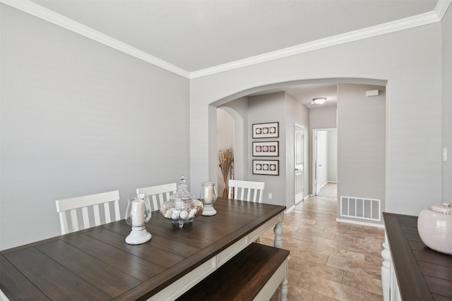 dining room with arched walkways, stone finish floor, crown molding, and visible vents
