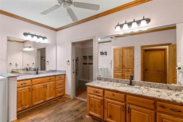bathroom with a shower stall, ornamental molding, wood finished floors, a ceiling fan, and a sink