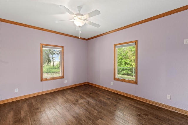 spare room with ornamental molding, dark wood-type flooring, a healthy amount of sunlight, and baseboards