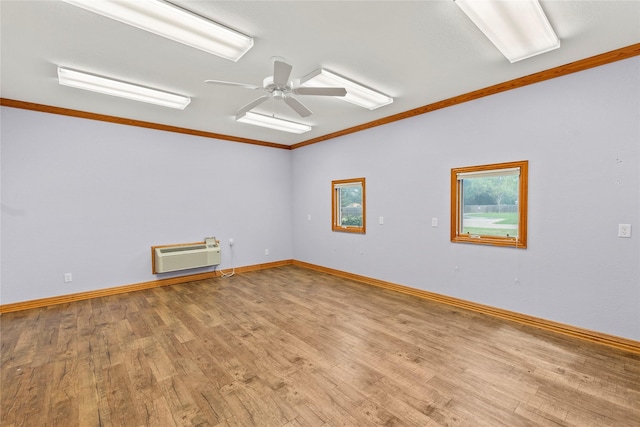 empty room featuring a wall mounted AC, baseboards, ornamental molding, wood finished floors, and ceiling fan