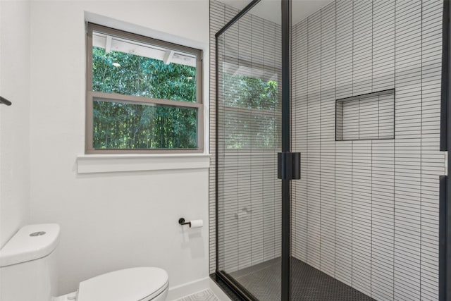 bathroom featuring toilet, a shower stall, and baseboards