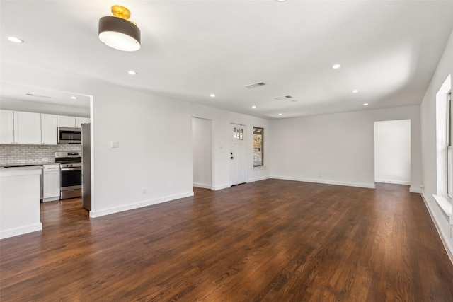 unfurnished living room with dark wood-type flooring, visible vents, recessed lighting, and baseboards
