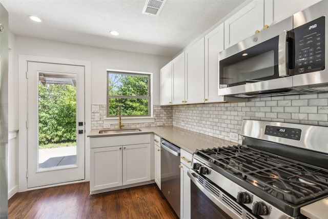 kitchen with dark wood-style floors, a sink, light countertops, white cabinets, and appliances with stainless steel finishes