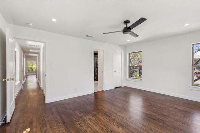 interior space featuring dark wood-style floors, a ceiling fan, visible vents, and baseboards