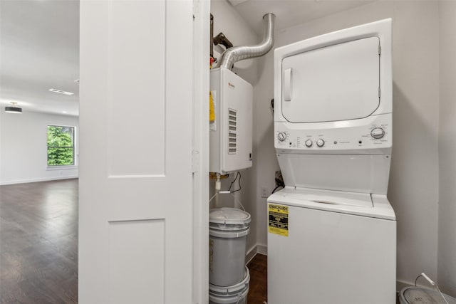 laundry room featuring baseboards, dark wood-style flooring, stacked washer / drying machine, and laundry area