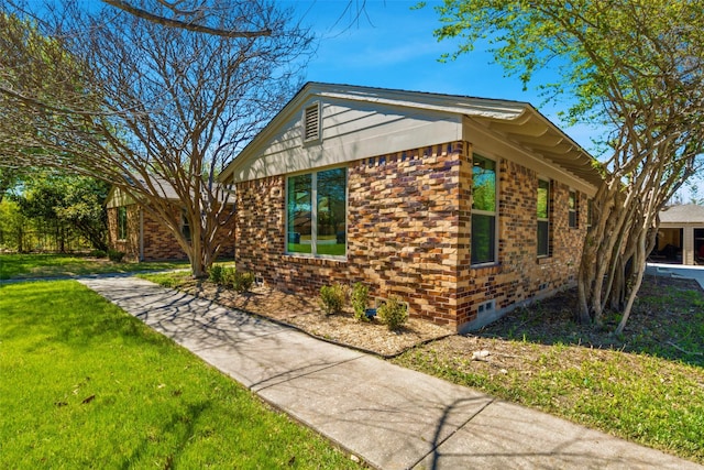 view of home's exterior with a yard, crawl space, and brick siding