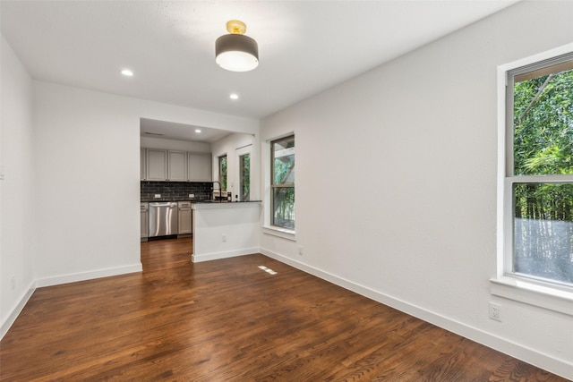 unfurnished living room with dark wood-type flooring, recessed lighting, and baseboards