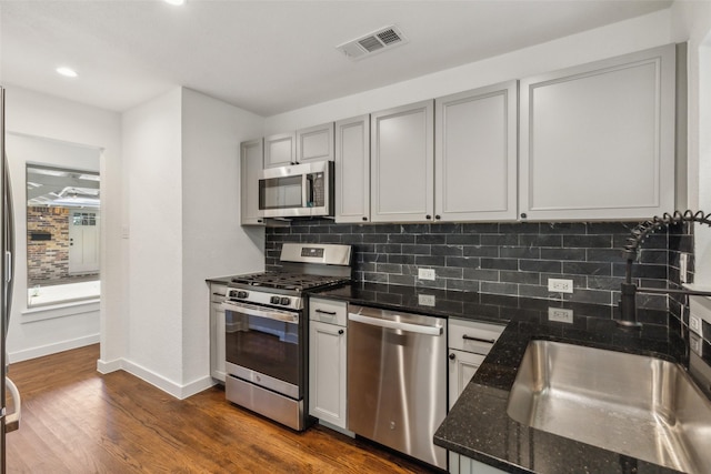 kitchen with a sink, dark wood-type flooring, tasteful backsplash, visible vents, and appliances with stainless steel finishes