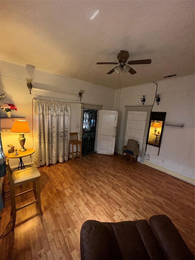 living room with a ceiling fan, wood finished floors, and a textured ceiling