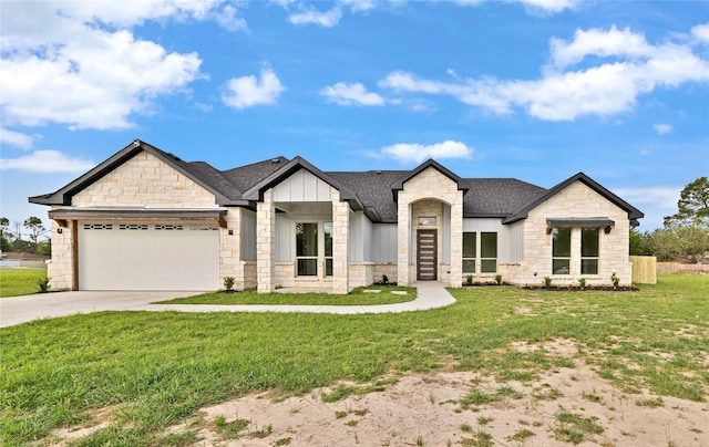 view of front of property with roof with shingles, driveway, stone siding, an attached garage, and a front yard