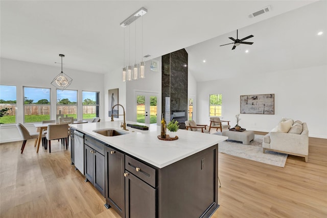 kitchen with a sink, a wealth of natural light, open floor plan, visible vents, and high vaulted ceiling
