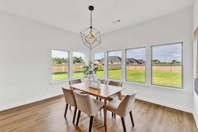 dining area with baseboards, light wood-style floors, visible vents, and an inviting chandelier