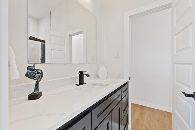 bathroom featuring baseboards, wood finished floors, and vanity