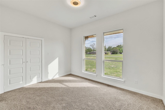 carpeted empty room with baseboards and visible vents
