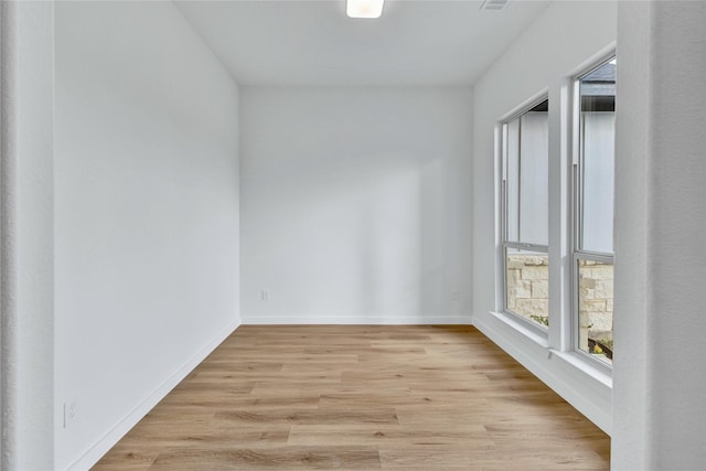 unfurnished room with plenty of natural light, light wood-style flooring, and baseboards