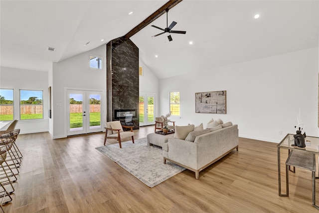 living area featuring high vaulted ceiling, a ceiling fan, wood finished floors, a fireplace, and baseboards