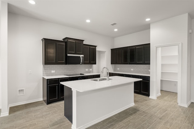 2608 Streamside Dr, Burleson, TX 76028 - kitchen featuring black electric cooktop, stainless steel microwave, tasteful backsplash, light wood-type flooring, and light countertops