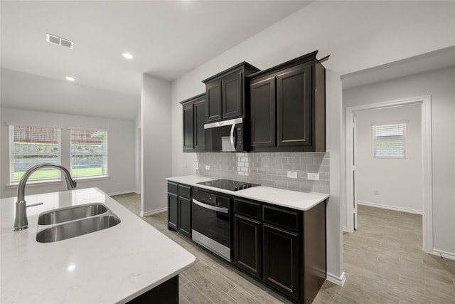 2608 Streamside Dr, Burleson, TX 76028 - kitchen with oven, stainless steel microwave, black electric stovetop, decorative backsplash, and light wood-type flooring