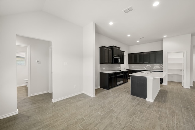 2608 Streamside Dr, Burleson, TX 76028 - kitchen featuring light countertops, dark cabinetry, decorative backsplash, light wood-type flooring, and recessed lighting