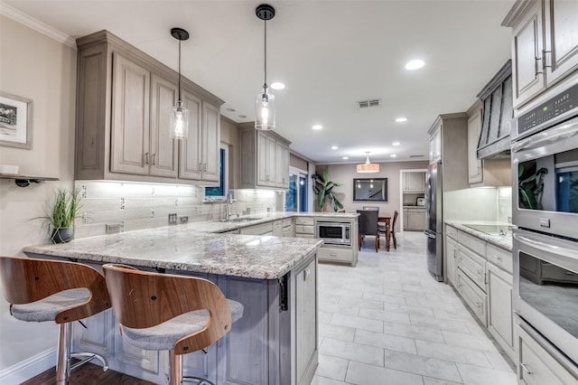 kitchen with visible vents, a peninsula, tasteful backsplash, appliances with stainless steel finishes, and a sink
