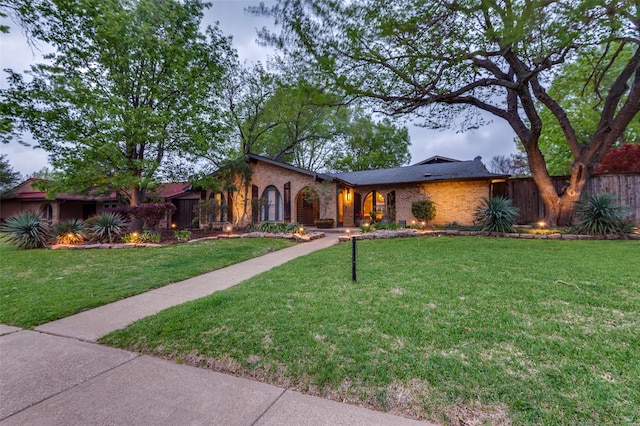 view of front of property with brick siding, a front yard, and fence