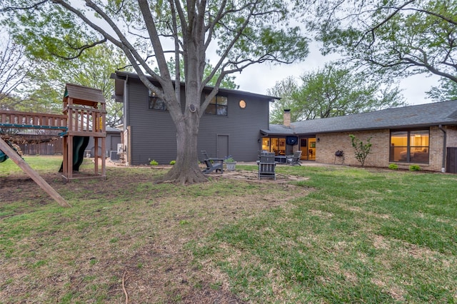 rear view of property featuring a lawn, a chimney, and brick siding