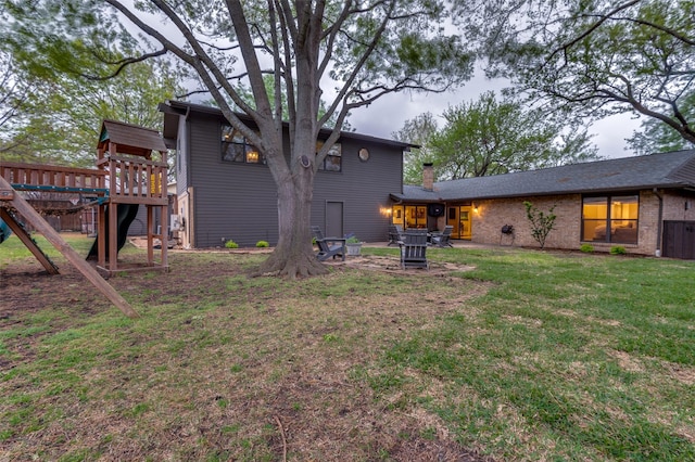 back of property featuring a yard and a playground