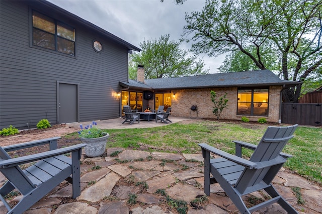 back of property with a patio, an outdoor fire pit, and a lawn