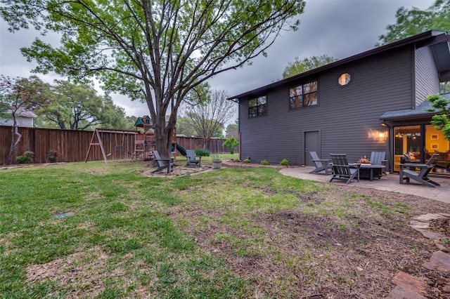 view of yard with a fire pit, a fenced backyard, a playground, and a patio area