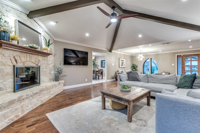 living area with visible vents, ornamental molding, wood finished floors, a stone fireplace, and vaulted ceiling with beams