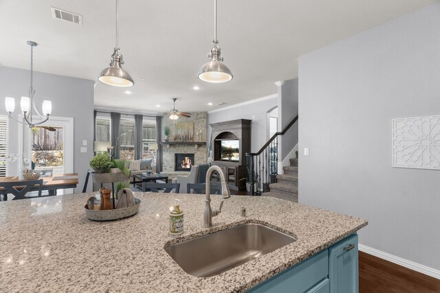 5604 Datewood Ln, Mckinney, TX 75071 - kitchen featuring a sink, a stone fireplace, blue cabinetry, dark wood finished floors, and baseboards