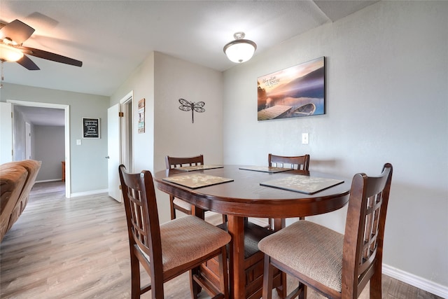 dining area with baseboards, light wood-style flooring, and ceiling fan
