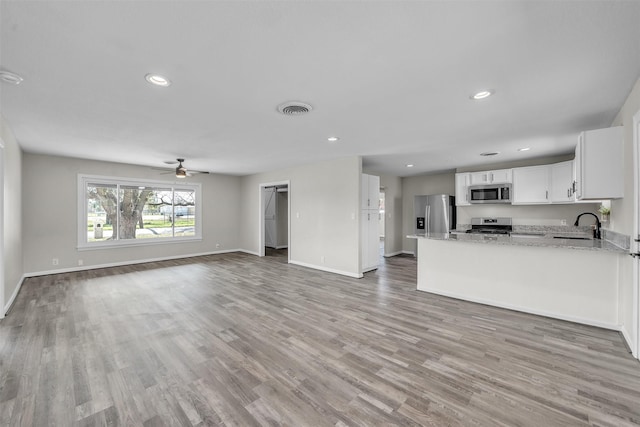 600 N Mill St, Bowie, TX 76230 - unfurnished living room with a sink, baseboards, light wood-style flooring, ceiling fan, and recessed lighting