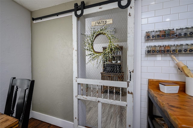 interior details featuring baseboards, a barn door, and a textured wall