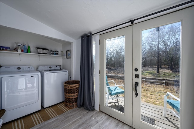 washroom featuring laundry area, washing machine and dryer, light wood-style flooring, and french doors