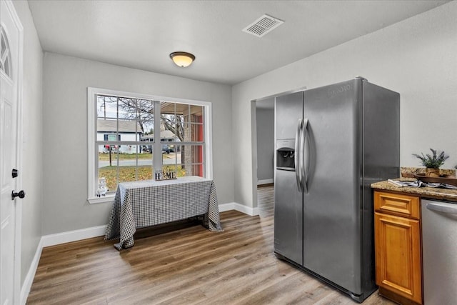 736 W Bullock Dr, Denison, TX 75020 - kitchen featuring appliances with stainless steel finishes, light wood finished floors, baseboards, brown cabinets, and stone countertops