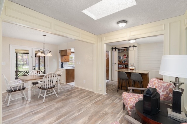 1 Cedar Bend Trl, Lucas, TX 75002 - dining room featuring a barn door, light wood-style floors, healthy amount of natural light, a textured ceiling, and a chandelier