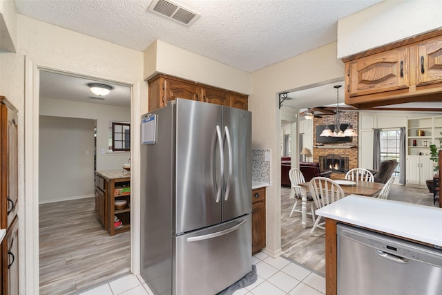 1 Cedar Bend Trl, Lucas, TX 75002 - kitchen with stainless steel appliances, a textured ceiling, a brick fireplace, light countertops, and light tile patterned floors