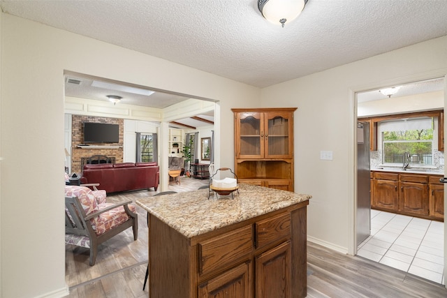 1 Cedar Bend Trl, Lucas, TX 75002 - kitchen with a fireplace, a sink, light wood-style flooring, open floor plan, and brown cabinets