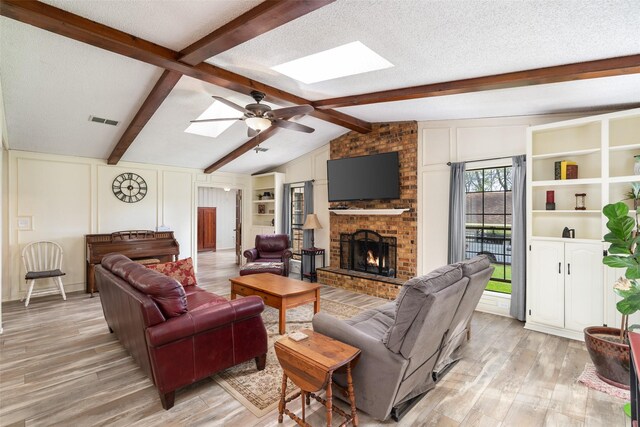 1 Cedar Bend Trl, Lucas, TX 75002 - living room featuring a skylight, light wood-type flooring, a brick fireplace, a ceiling fan, and a textured ceiling