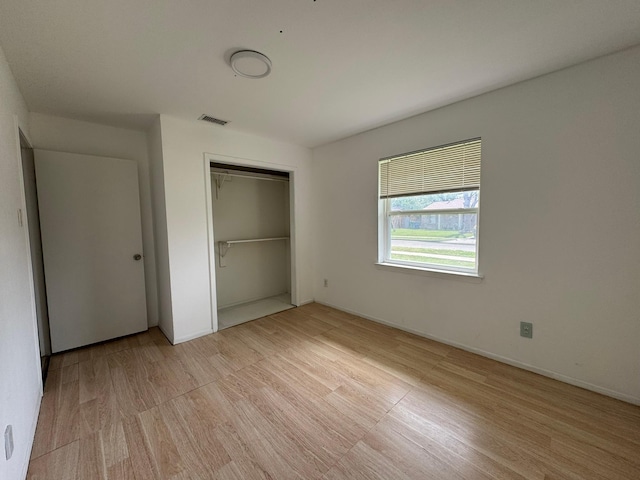 unfurnished bedroom with visible vents, a closet, and light wood-style flooring