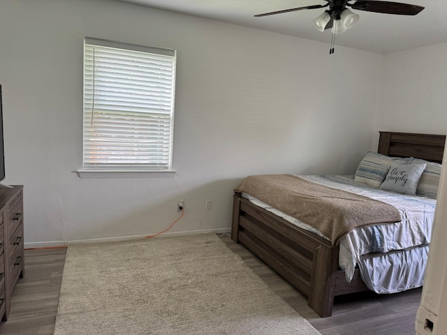 bedroom featuring baseboards, wood finished floors, and a ceiling fan