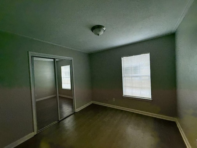 132 London Ln, Glenn Heights, TX 75154 - unfurnished bedroom with dark wood-style flooring, baseboards, a closet, and a textured ceiling