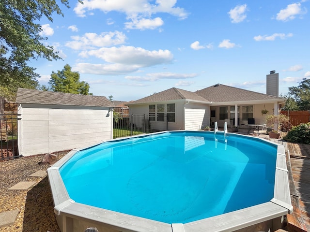 view of pool with an outdoor structure, a fenced in pool, a storage shed, and fence