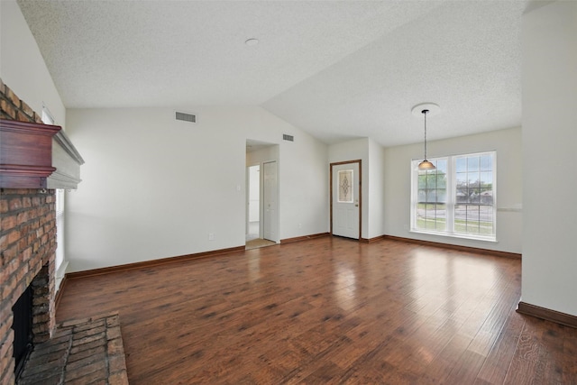 5912 Oregon Trl Ct, Haltom City, TX 76148 - unfurnished living room featuring lofted ceiling, a textured ceiling, visible vents, a brick fireplace, and wood finished floors