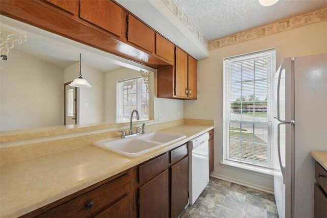 5912 Oregon Trl Ct, Haltom City, TX 76148 - kitchen with light countertops, a sink, a textured ceiling, stone finish floor, and white appliances