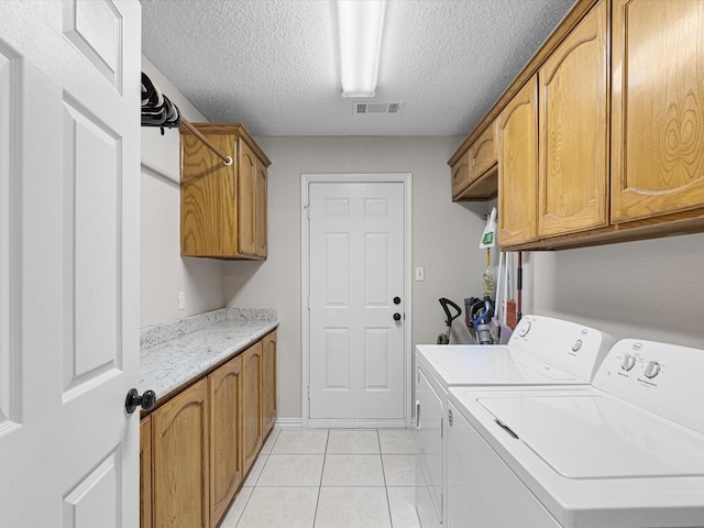 laundry area featuring cabinet space, a textured ceiling, light tile patterned floors, visible vents, and washing machine and dryer