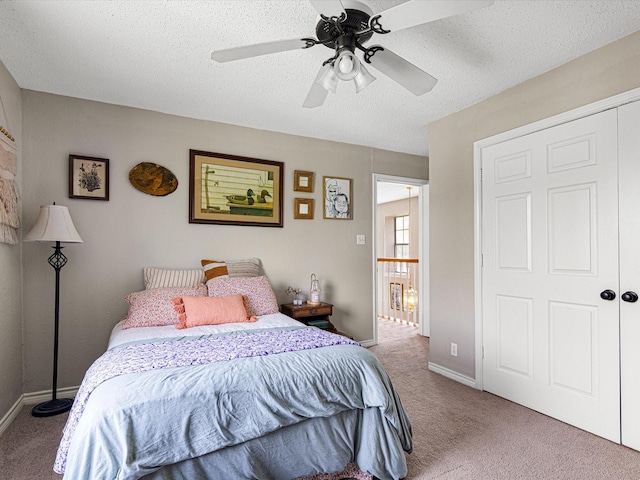 carpeted bedroom with baseboards, ceiling fan, and a textured ceiling