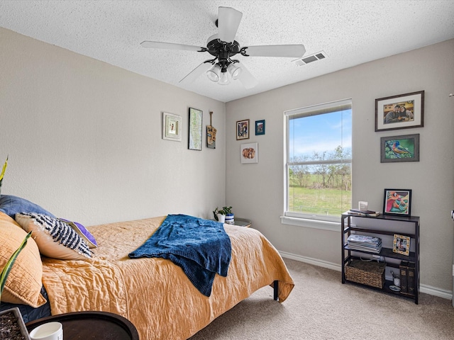 bedroom featuring visible vents, baseboards, ceiling fan, a textured ceiling, and carpet